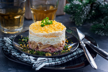 Salad in layers with canned mushrooms, smoked chicken and cheese on a black plate, horizontal
