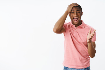 Guy screams punching head and pointing with palm at camera as being devestated and displeased with bad score watching game regreting and feeling upset yelling disappointed over gray background