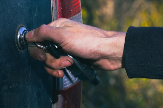 Man closes or opens the trunk of the car with a key