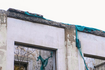 Destroyed building, housing in disrepair, demolition of the old house on grey sky background.