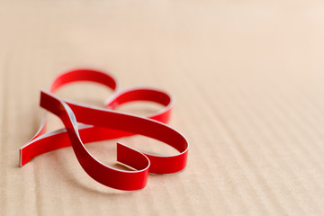 Two homemade paper red hearts on a beige cardboard background, the symbol of Valentine's Day.