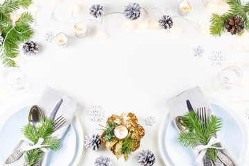 Christmas table setting with plates, silverware, presents, candles and decorations