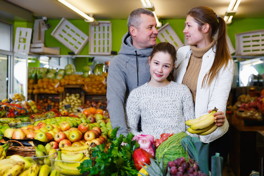 Nice family with daughter buying ripe bananas