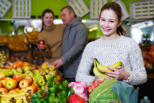 Positive girl with parents choosing fruits