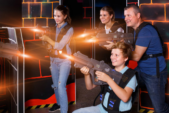 joyous young parents and children with laser pistols playing las