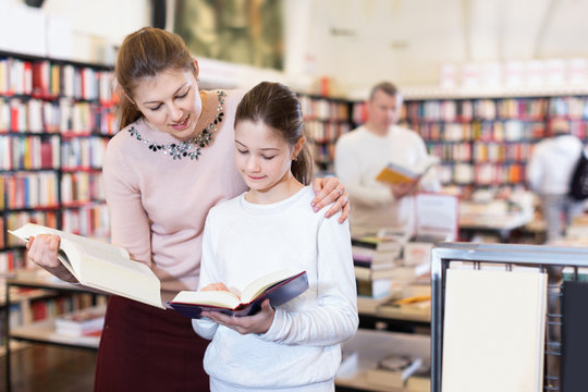 Friendly family of mother and daughter browsing books together in bookstore