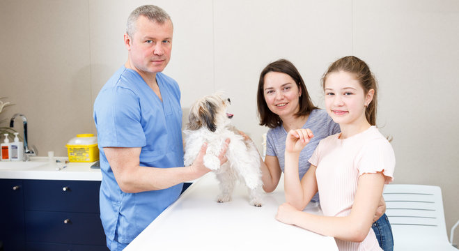 Happy family with dog consulting by veterinarian