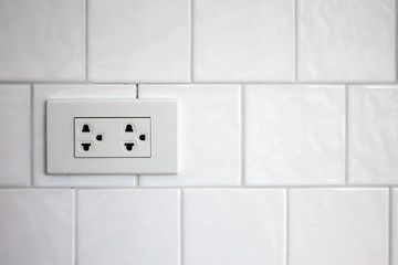 electrical plug on white brick wall with soft-focus and over light in the background
