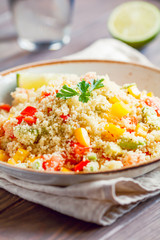 Couscous salad with fresh red and yellow bell peppers, avocado, tomatoes and lime. The concept of vegetarian and healthy food.