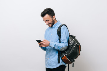 Portrait of happy young man using a smartphone and wears backpack