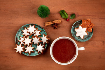 Zimsterne, traditional German Christmas cinnamon star cookies, shot from the top on a dark rustic wooden background with hot chocolate and spices