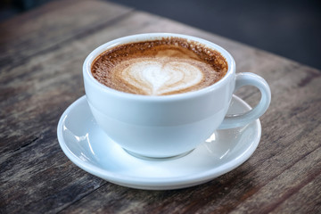 Closeup image of a white cups of hot coffee on vintage wooden table in cafe