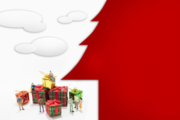 A group of miniature people and a pile of present box. christmas concept. With christmas tree text box.