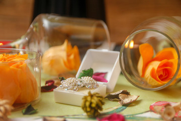 Romantic composition with wine glass, roses, jewelry, candles and bottle of wine. Candle light and dry leaves of flower on the table.