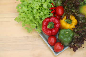Closeup of organic fresh vegetables in ceramic plate on wooden table. Preparation for healthy food cooking. 
