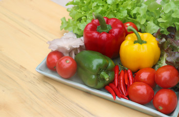 Closeup of organic fresh vegetables in ceramic plate on wooden table. Preparation for healthy food cooking. 