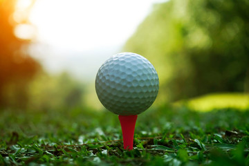 Golf ball on tee in beautiful golf course at sunset background.