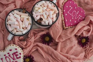 Romantic breakfast for valentine day. A delicious drink of marshmallows and heart-shaped cookies. Breakfast for lovers on a white table with pink textile