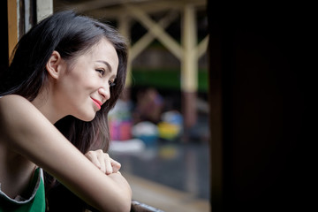 Asian woman traveler has looking to outside in the train with happiness at Hua Lamphong station at Bangkok, Thailand.