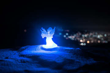 christmas angel on blur bokeh city lights at night on background. Little white guardian angel in...