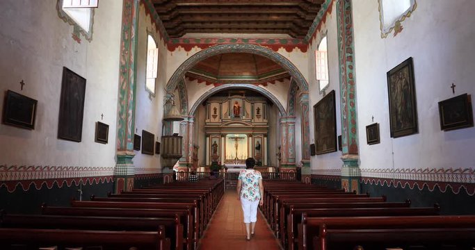 Woman walks away Old Mission San Luis Rey church California. Mission San Luis Rey was a Spanish mission. Founded 1798. Active parish church congregation meet and worship. 