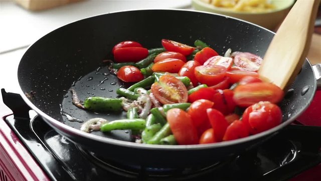 ooking vegetables cherry tomatoes green bean onion  frying pan 
