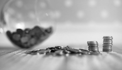 Coins in a jar on the floor. Accumulated coins on the floor. Savings in piles.