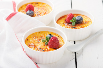 Creme brulee. Traditional French vanilla cream dessert with caramelised sugar on top and fresh berry. - Image
