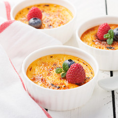 Creme brulee. Traditional French vanilla cream dessert with caramelised sugar on top and fresh berry. - Image