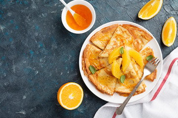 Crepes suzette - pancakes with orange sauce on dark blue background.