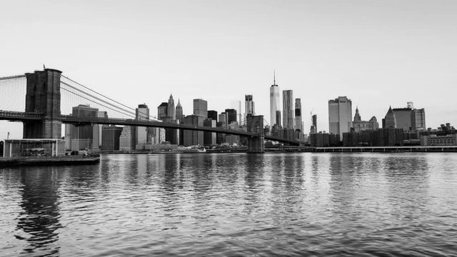 New York, USA. View of Manhattan bridge and Manhattan in New York, USA in the morning. Clear blue sky with skyscrapers. Time-lapse at sunrise. Black and white