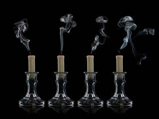Four extinguished candles in candlesticks from glass