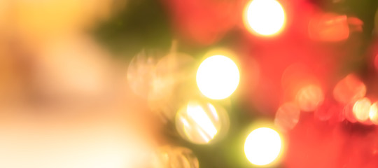 Christmas bokeh blur background with blurry x’mas tree party night light decoration ornate in warm red green gold color for holiday greeting card backdrop