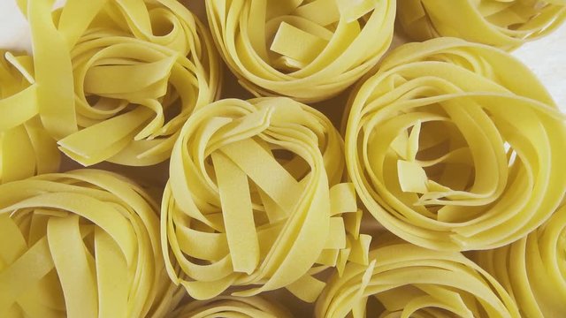 On a wooden background pasta Lasaghette Tagliatelle Papardelle rotate clockwise top view