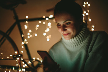 Portrait of girl using smartphone with christmas decoration in background