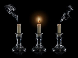 Two extinguished and one burning candle