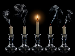 Four extinguished candles and one burning candle