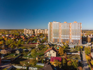 Naklejka premium High-rise residential building under construction among private houses in Russia