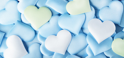Fototapeta premium Valentine's Day. Blue heart shape backdrop. Abstract holiday Valentine background with blue, green and white pastel colors satin hearts. Love concept. Flat lay, top view 