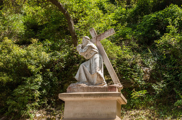 Cross-carrying pilgrim sculpture at Montserrat Abbey. Spain
