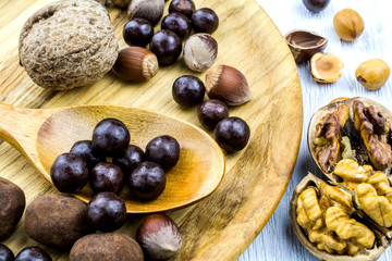 Utensils made of wood, nuts and chocolates close up.