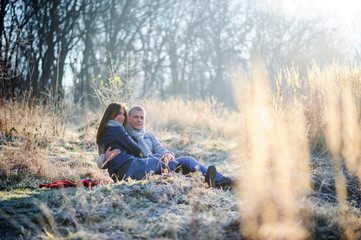 Naklejka na ściany i meble Young pretty fashion sensual couple in love sitting in winter cold field
