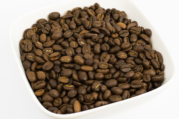 Roasted coffee beans in a white square bowl