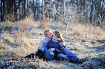 Naklejka na ściany i meble Young pretty fashion sensual couple in love sitting in winter cold field