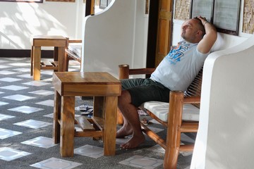 A man relaxes on a bamboo sofa on the terrace in the tropics