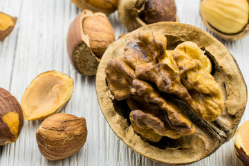 Chopped walnuts, hazelnuts lie in a white wooden background by close up.