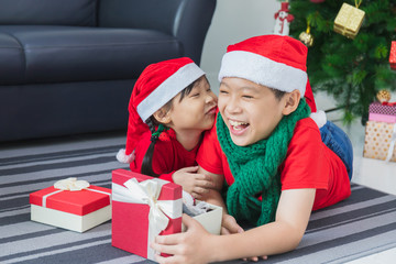 Asian boy and girl playing and decorating Christmas tree in white room at home with gift box.Smiling face and happy to celebrate festivel new year holiday with family.