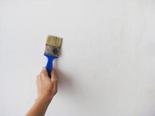 Painter Painting a House Wall with Small Paint Brush in Hand at Apartment Room for Repairs. White Wall Paint in Building, Construction, Renewing, Painting and Renovation in the House Concept Theme