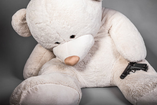 toy bear with a gun, suicide concept, image on a gray background