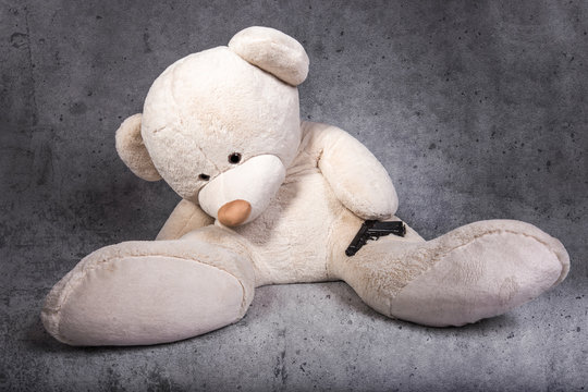 toy bear with a gun, suicide concept, image on a concrete background